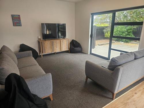 a living room with two couches and a tv at Refresh At Fraser in Twizel
