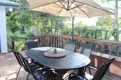 a table with chairs and an umbrella on a patio at 5-min walk to Village - Havelock North Holiday Home with Spa Pool in Havelock North
