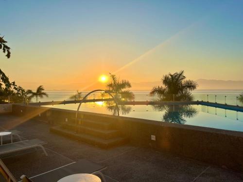 a swimming pool with a sunset in the background at Beautiful Oceanview Apartment in Zantamar in Cruz de Huanacaxtle