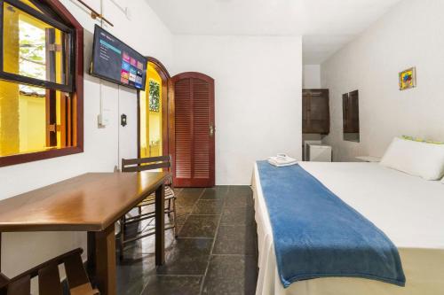 a bedroom with a bed and a table and a desk at Pousada Acqua Marina in Paraty