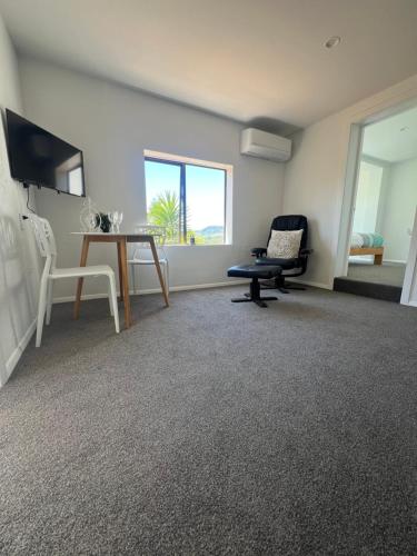 a living room with a table and a chair and a desk at Sunny hillside central Nelson hideaway with city to sea views in Nelson