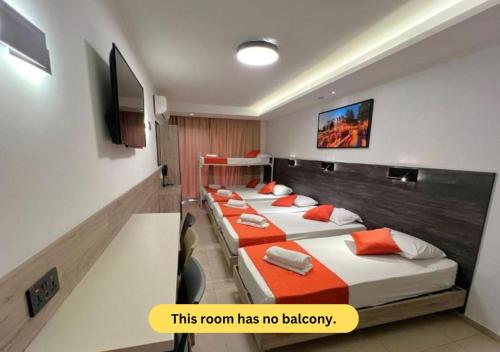 a room with four beds and a tv on the wall at Bayside A Apartments in St Julian's