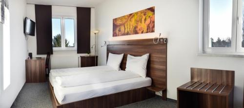 Schlafzimmer mit einem Bett mit einem Kopfteil aus Holz in der Unterkunft Hotel Fabrik Vösendorf in Vösendorf