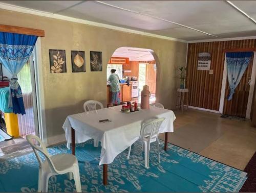 a room with a table and chairs and a person in the kitchen at JayDees Home Retreats Homestay in Naselesele