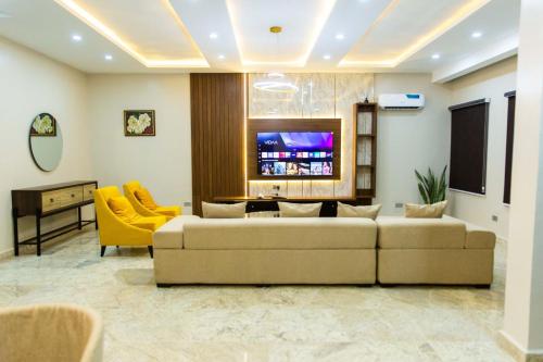 a living room with a couch and a tv at Calini Luxury 2 Bedroom Flat - Sunflower Escape in Abuja