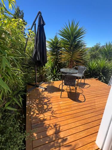 a wooden deck with a table and an umbrella at Sunny hillside central Nelson hideaway with city to sea views in Nelson