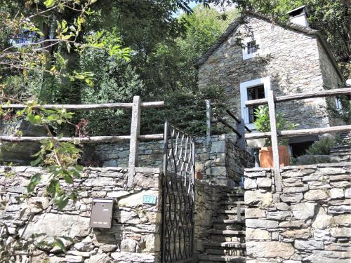 an old stone house with a gate and a fence at Rustico Gatto by Fewotessin in Cugnasco