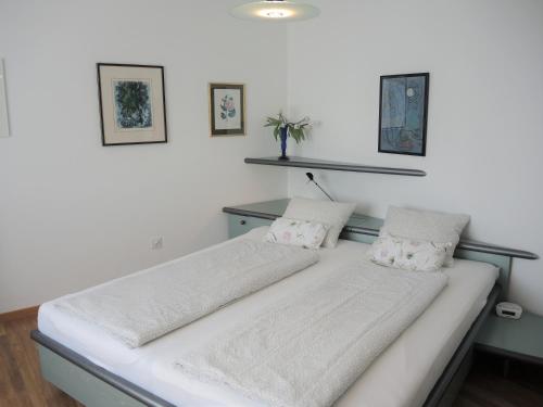 a bed with white sheets and pillows in a room at Casa Lydia by Fewotessin in Brione sopra Minusio