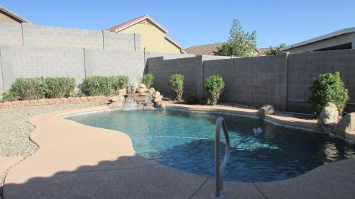 a swimming pool with a waterfall in a backyard at Cozy home near freeways w pool BBQ in Peoria