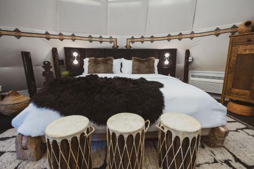 a bedroom with a large bed with two stools at Lobo Tipi at El Mistico Ranch in Nogal