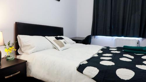 a bedroom with a bed with a black and white comforter at Morden Model Accommodation in Mitcham
