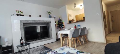 un salon avec une cheminée et une table avec des chaises dans l'établissement Apartament Słoneczny 11, à Szklarska Poręba