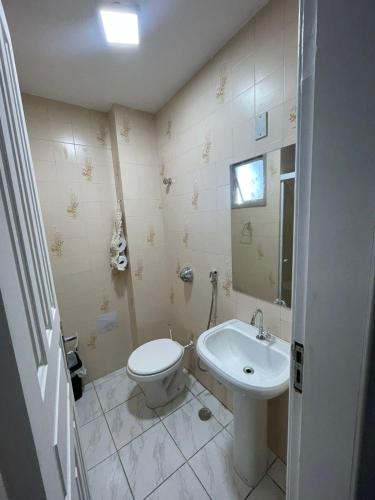 a bathroom with a toilet and a sink at Apartamento grande FRENTE MAR in Guarapari