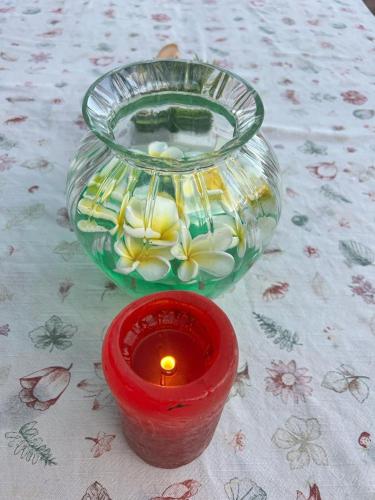 a candle and a glass bowl with flowers on a table at Principauté in Gorée