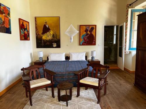 a dining room with a table and chairs and paintings at Principauté in Gorée