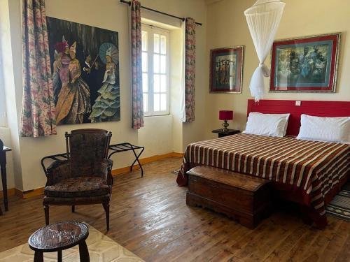 a bedroom with a bed and a chair and a painting at Principauté in Gorée