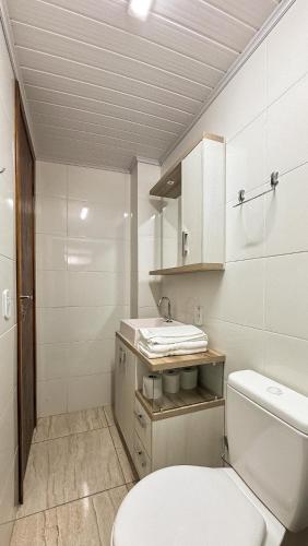 a white bathroom with a toilet and a sink at Atlantida Johsil Hotel in Xangri-lá