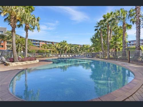 a large swimming pool with palm trees in a resort at Quiet and convenient in Sydney