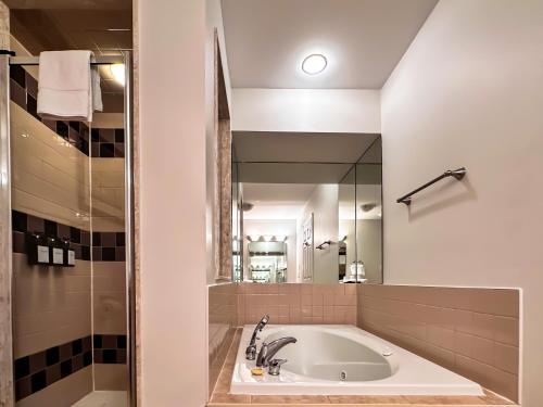 a bath tub in a bathroom with a large mirror at Spa Golf Bike in Collingwood