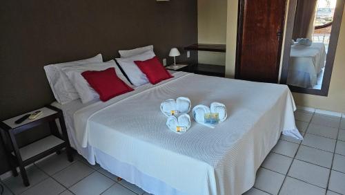 a bedroom with a bed with two towels and slippers at Hotel Pousada Cumbuco Gold in Cumbuco