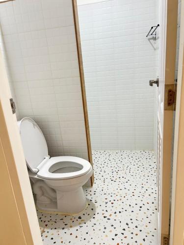 a bathroom with a toilet and a tiled floor at ร เรือ รีสอร์ท in Ban Khao Noi