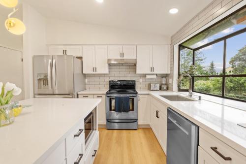 a kitchen with white cabinets and a sink and a stove at Spacious Modern Retreat w Game Room and Yard in Lynnwood