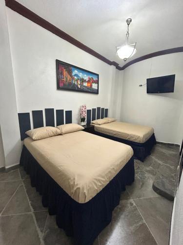 a bedroom with two beds and a flat screen tv at Hostal Casa de Grethel in Flores