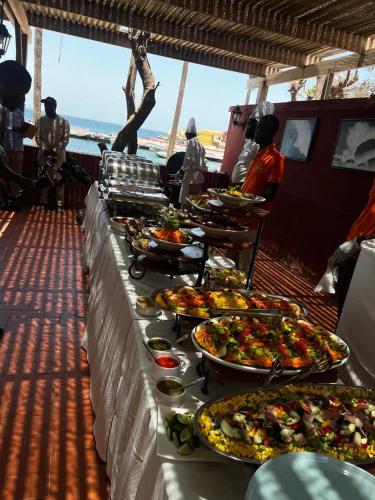 a buffet line with many plates of food on a boat at Principauté in Gorée