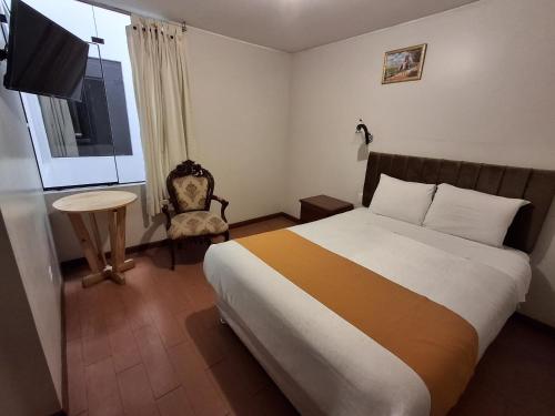 a bedroom with a bed and a chair and a window at Hotel Sideral AQP in Arequipa