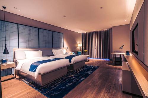 a bedroom with a large bed and a television at Echarm Hotel Fujian Hongtuo Central City in Tengcheng