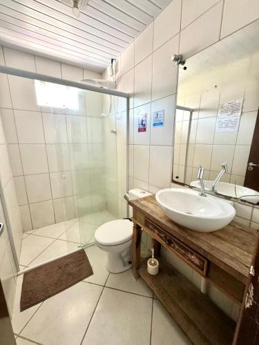 a bathroom with a sink and a toilet and a mirror at Quarto em Florianópolis in Florianópolis