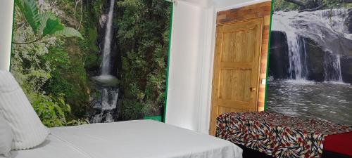 a bedroom with a painting of a waterfall next to a door at Eco-HOTEL HOGAR EN LA MONTAÑA HOME SWEET HOME in La Vega