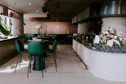 a restaurant with a bar with green chairs and flowers at Midnight Hotel, Autograph Collection in Canberra