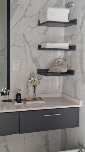 a bathroom with a sink and a shelf with towels at Hotel Boutique Gualamba in General Pinedo