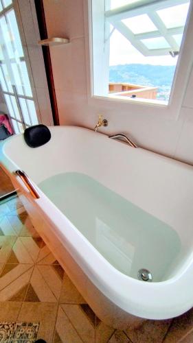 a white bath tub in a bathroom with a window at Mouton Blanc Campos do Jordão in Campos do Jordão