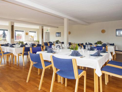 a dining room with white tables and blue chairs at Apartment in Holiday park- shared kitchen in Ulfborg
