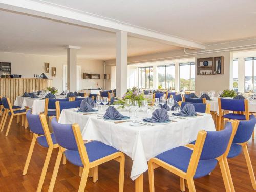 a banquet hall with white tables and blue chairs at Apartment in Holiday park- shared kitchen in Ulfborg