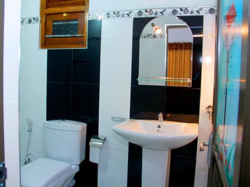 a bathroom with a white toilet and a sink at Sanda Hiru Guest in Mirissa
