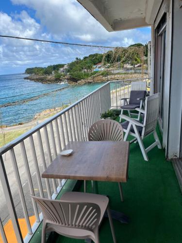 a balcony with chairs and a table and the ocean at La résidence du sportif Bernard in Anse-Bertrand