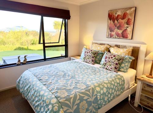 a bedroom with a bed and a large window at Acacia Bay Lodge- Private Manor with Lake and Garden views in Taupo