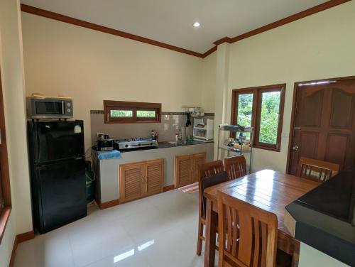 a kitchen with a table and a black refrigerator at Links Sunset Beach House in Amphoe Koh Samui