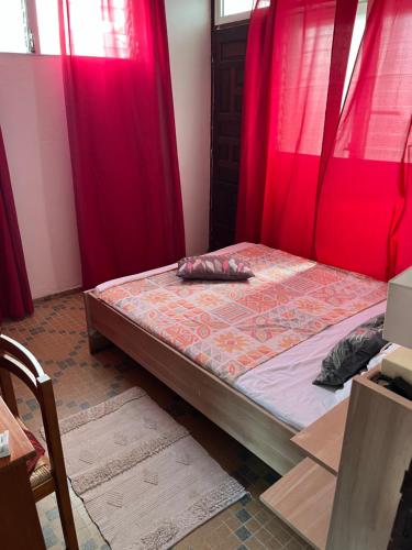 a bed in a room with red curtains at La résidence du sportif Bernard in Anse-Bertrand
