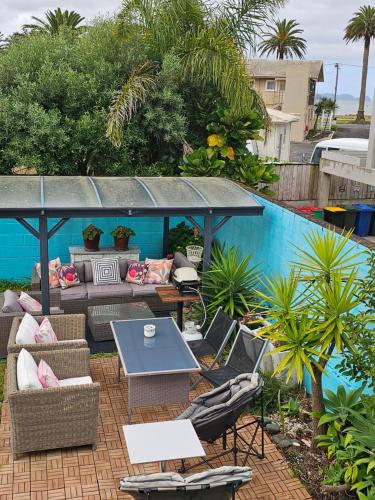 um pátio com mesa e cadeiras ao lado de uma piscina em Albert Number 6 em Whitianga