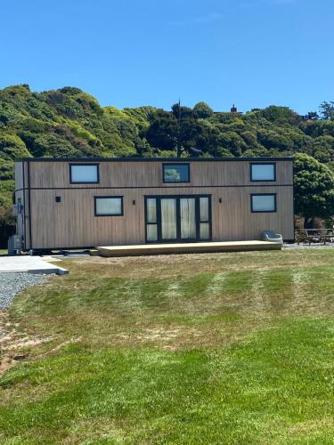 a large building with windows on top of a grass field at Seaspray Cabin in Hinahina