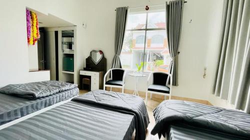 ein Schlafzimmer mit zwei Betten und einem Tisch und einem Fenster in der Unterkunft Lucky 2 Hotel in Trà Vinh