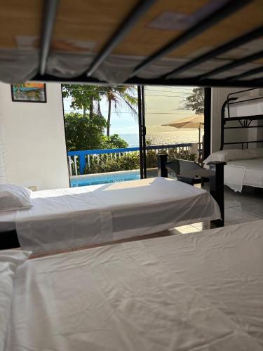 two beds in a bedroom with a view of the ocean at Atardecer D Oro, Casa de playa in Esparza