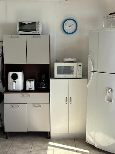 a kitchen with white cabinets and a clock on the wall at Atardecer D Oro, Casa de playa in Esparza