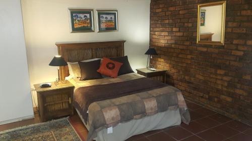 a bedroom with a bed with a brick wall at Albatross B&B in Benoni