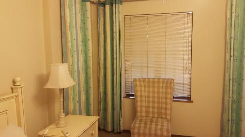 a bedroom with a chair and a lamp and a window at Albatross B&B in Benoni