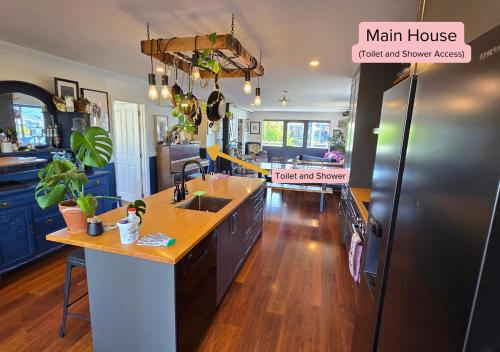 a kitchen with blue cabinets and a black refrigerator at Tairua Garden Hideaway - Homestay with Private Room in Tairua